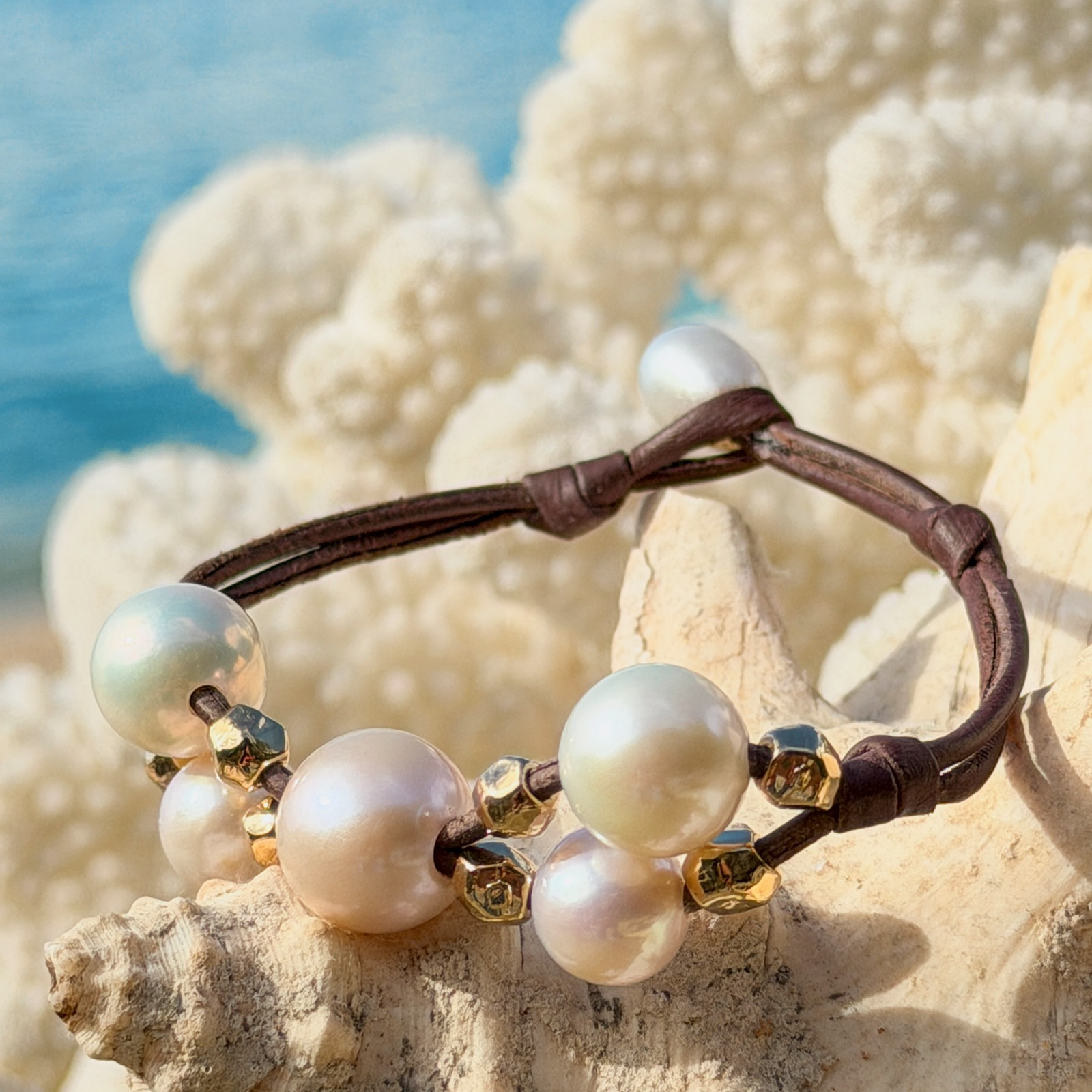 Bracelet Papillon en cuir, perles blanches et billes dorées, bijou posé sur un fond naturel