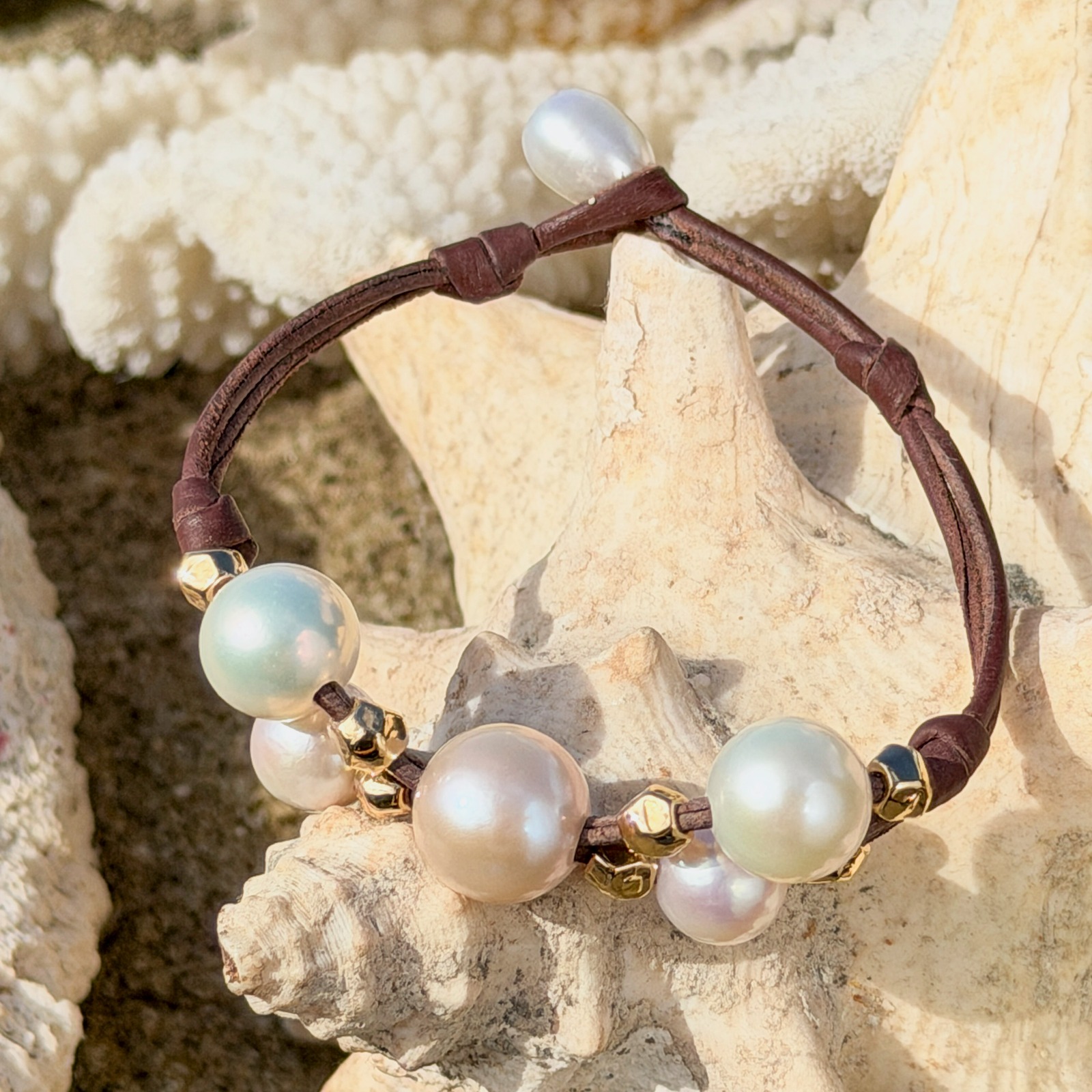 Bracelet Papillon en cuir, perles blanches et billes dorées, bijou posé sur un fond naturel