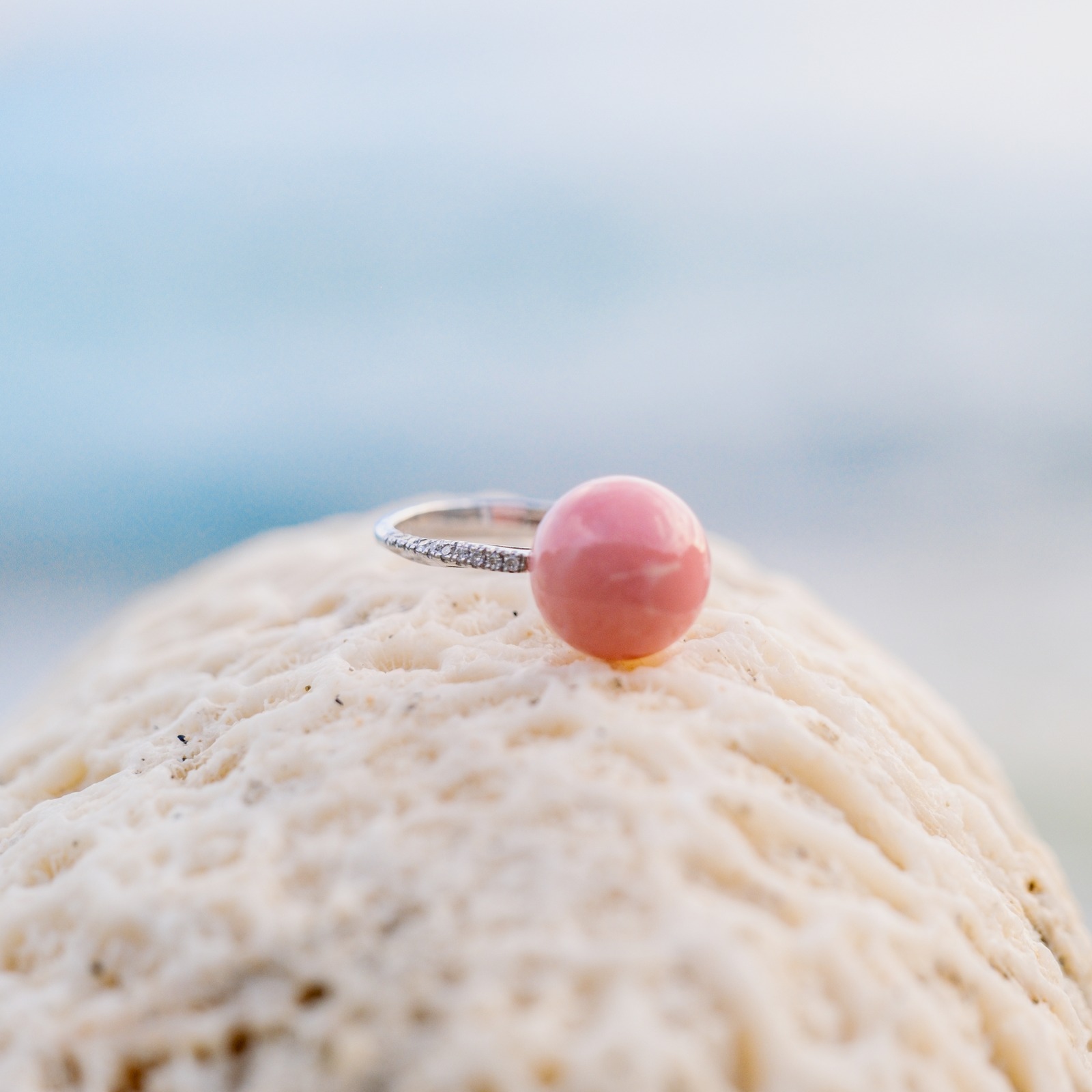 Bague en or blanc, perle de lambis rose et diamants, bijou posé sur un fond naturel