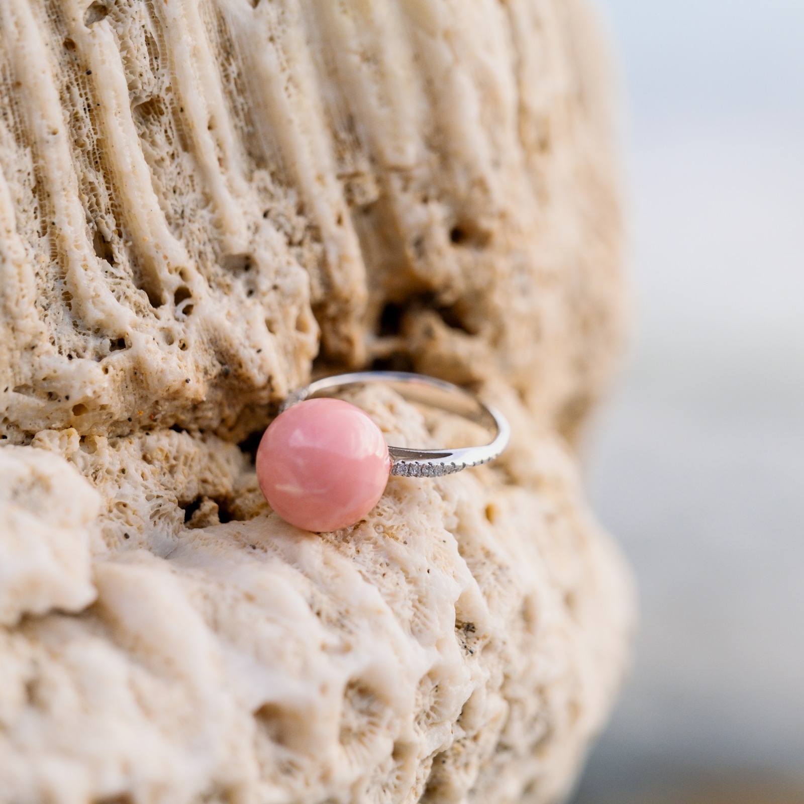 Bague en or blanc, perle de lambis rose et diamants, bijou posé sur un fond naturel