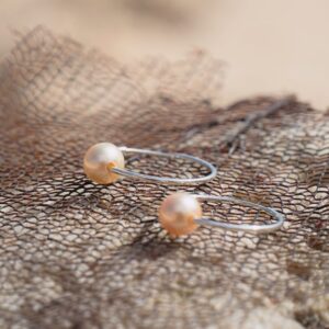 Silver hoop earrings with golden South Sea pearls, jewelry on a natural background