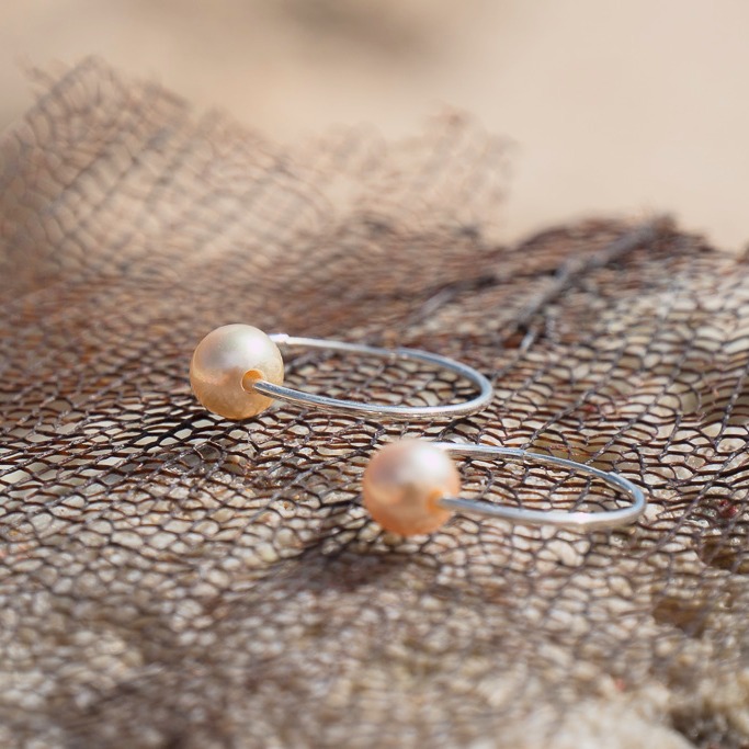 Silver hoop earrings with golden South Sea pearls, jewelry on a natural background