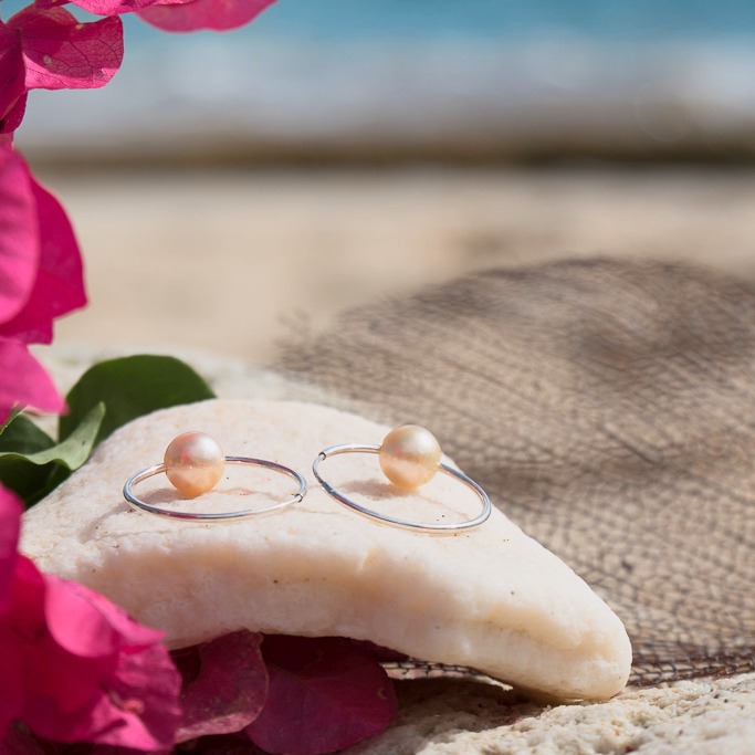 Silver hoop earrings with golden South Sea pearls, jewelry on a natural background