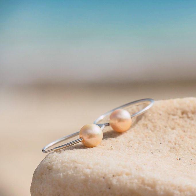 Silver hoop earrings with golden South Sea pearls, jewelry on a natural background